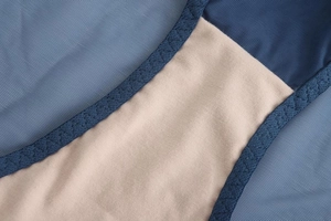 Detailed close-up of blue lace mesh fabric and reinforced stitching on lingerie