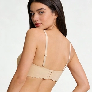 Seamless beige wireless bra featuring thin adjustable straps and scalloped wave edges