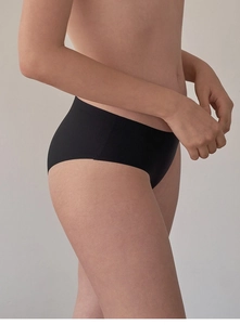 Detail view of seamless black low-rise panties on model showing smooth elastic fabric