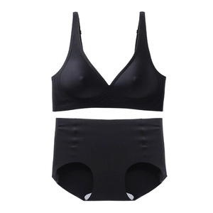 Flat lay of seamless black bra set with thin straps and high-waisted briefs on white backdrop