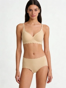 Detail of nude seamless lingerie set featuring scalloped laser-cut edges on a model