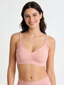 Detail of seamless pink bra with wavy scalloped edges and V-neckline on model