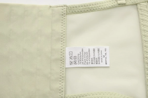 Dettaglio dell'interno del reggiseno in raso verde con etichetta di lavaggio e tessuto mesh