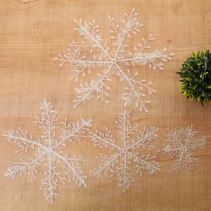 Close-up of pink snowflake ornaments with glitter wire on rustic wood surface