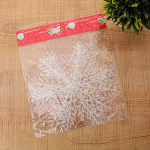 White plastic Christmas snowflake decoration with glitter in red festive packaging