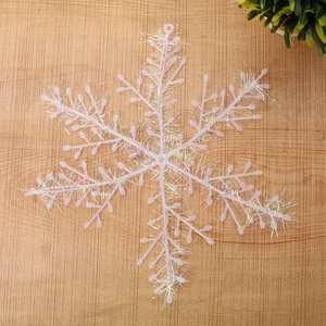 Detailed view of a pink iridescent snowflake ornament hanging on a light wood background