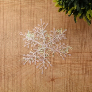 Detailed view of white plastic snowflake decoration with colorful laser filament on wood