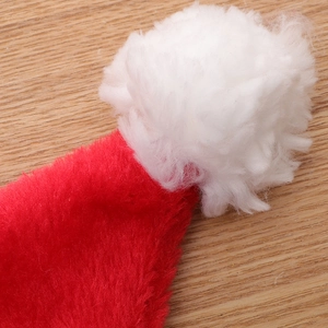 Premium plush red Christmas hat with white pom-pom detail on wooden background