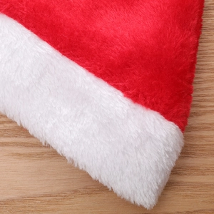 Classic plush Christmas hat with soft red fabric and white faux fur trim on wood background