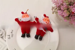 Close-up of two miniature Santa Claus ornaments with red velvet coats and gold hanging strings