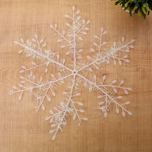 Pink snowflake Christmas tree ornament with colorful wire details on wooden background