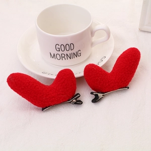 Detail of red plush heart-shaped hair clips with fuzzy texture and metal duckbill clip