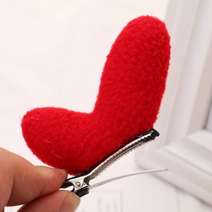 Detail view of a red heart-shaped plush hair clip with a silver metal duckbill base