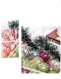 Detail of transparent PET Christmas balls with glitter spirals and green decorative tinsel