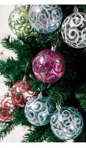 Detail view of transparent Christmas balls with colorful glitter spiral patterns on a tree