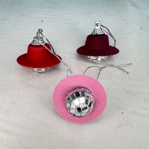 Three disco ball cowboy hat ornaments in red, burgundy and pink colors for party decoration