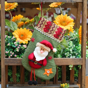 Knitted green Christmas stocking with 3D Santa doll and rustic floral background decoration