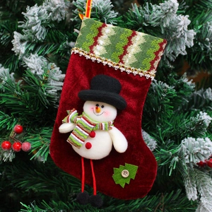 Plush red Christmas stocking with snowman doll on a snowy tree background