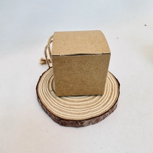 Detail of square kraft paper gift box with hemp rope on a natural wooden log slice base