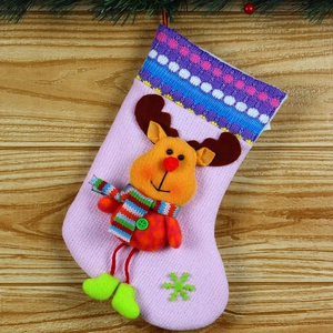 Detailed view of a pink knitted Christmas stocking with a 3D plush reindeer on wood