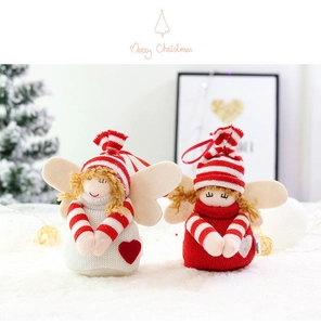 Close-up of knit Santa Claus angel dolls with striped hats and felt wings on white fur