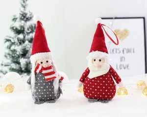 Close-up of small plush Santa ornaments with knitted hats and scarves for Christmas tree