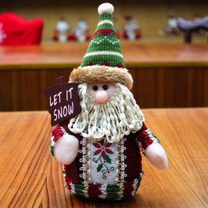 Detail of Santa Claus plush with green knit hat and Let It Snow wooden sign decoration