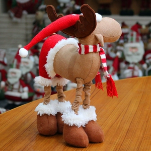 Detailed view of Christmas reindeer doll with red striped scarf and knit hat on wooden table