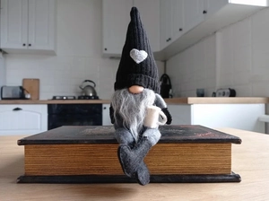 Detailansicht eines Weihnachtswichtels mit Herzmütze und Becher auf einem Buch