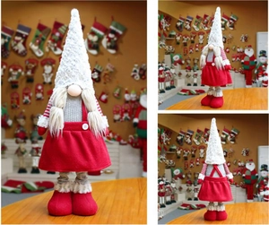 Detail view of a Christmas gnome doll with white braids and red overall dress for holidays