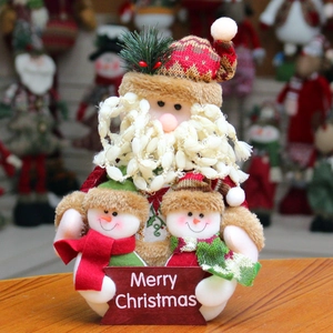 Cute Santa Claus plush doll holding snowmen with Merry Christmas sign on wood table