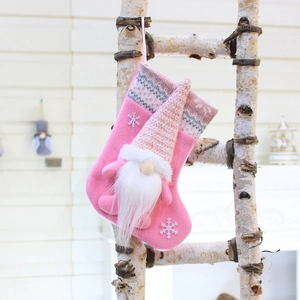 Detail of pink knitted Christmas stocking featuring a 3D gnome and white snowflakes