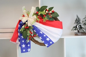 Close-up of patriotic wreath with rattan base, berries, and stars and stripes burlap bow