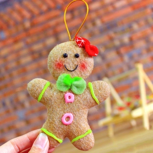 Close-up of a gingerbread man plush ornament with a red bow and green tie for Christmas