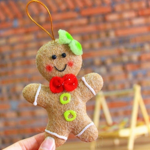 Close-up of a handmade gingerbread man plush ornament with a festive green bow tie