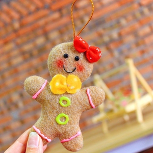 Macro shot of felt gingerbread man ornament with red bow and gold hanging string