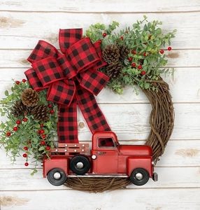 Détail de couronne de Noël avec camion rouge, pommes de pin et nœud en tissu écossais