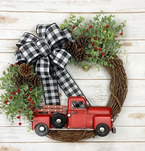 Détail de la couronne de Noël avec camion rouge, pommes de pin et nœud en tissu à carreaux