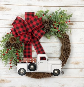 Détail d'un camion blanc vintage et d'un nœud à carreaux rouges sur une couronne de Noël