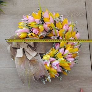 Macro shot of a 40cm faux tulip wreath with pink flowers and a rustic burlap bow