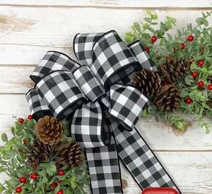 Détail de couronne de Noël avec nœud à carreaux, pommes de pin et baies sur bois