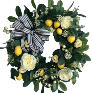 Handcrafted yellow lemon and white rose wreath with black striped ribbon on white background