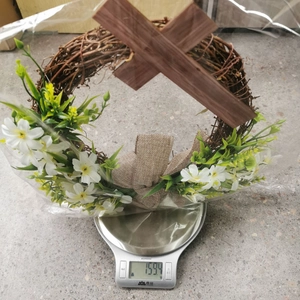 Detailed view of an Easter cross wreath being weighed on a scale with rustic bow and flowers