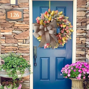 Artificial spring tulip wreath with burlap bow hanging on a blue door for home wall decor