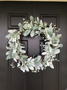 Detailed view of silver leaf greenery and white flowers on a wooden wicker wreath frame