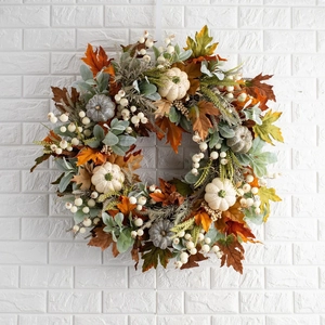 Couronne d'automne avec citrouilles blanches et feuilles d'érable sur mur de briques