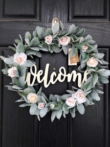 Detail of 30cm Easter wreath with pink roses, green leaves and wooden Welcome sign on black door