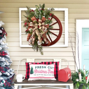 Teardrop Christmas wreath with pine cones and plaid bow on wooden wheel door hanger