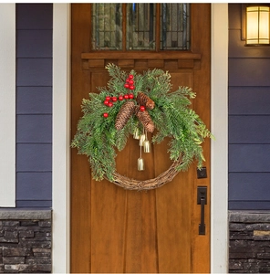 Close-up of Christmas wreath with pine cones and golden bells on a brown wooden door