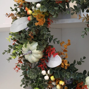 Harvest pumpkin wreath with eucalyptus leaves and colorful berries for autumn home decor